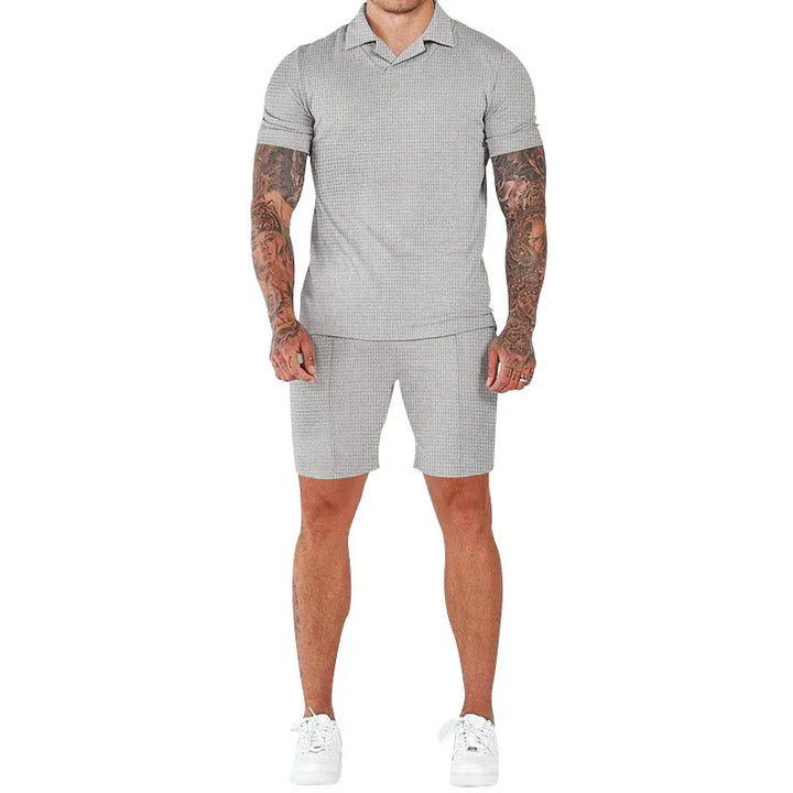 Man wearing light gray short-sleeve polo shirt and matching shorts with white sneakers