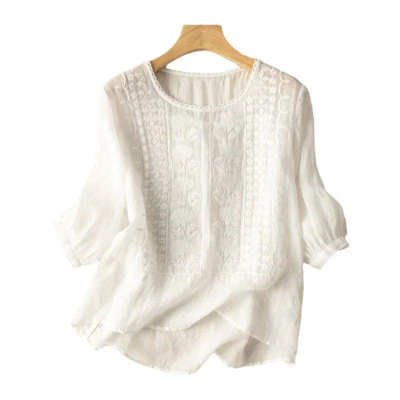 white embroidered lightweight blouse with puff sleeves on wooden hanger