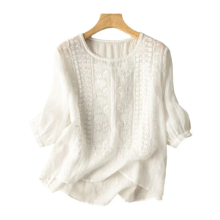 white embroidered lightweight blouse with puff sleeves on wooden hanger