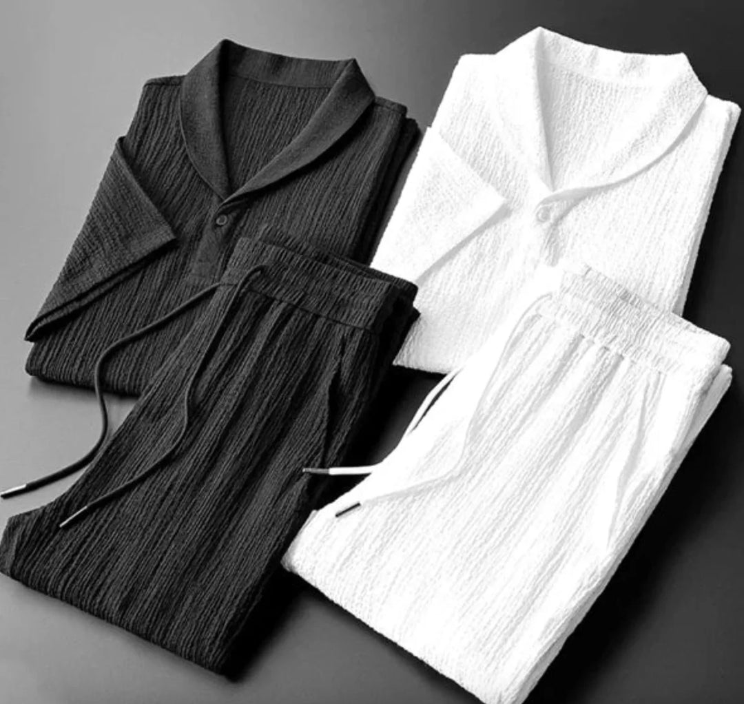 Folded black and white textured pajamas with short sleeves and drawstring pants on gray background