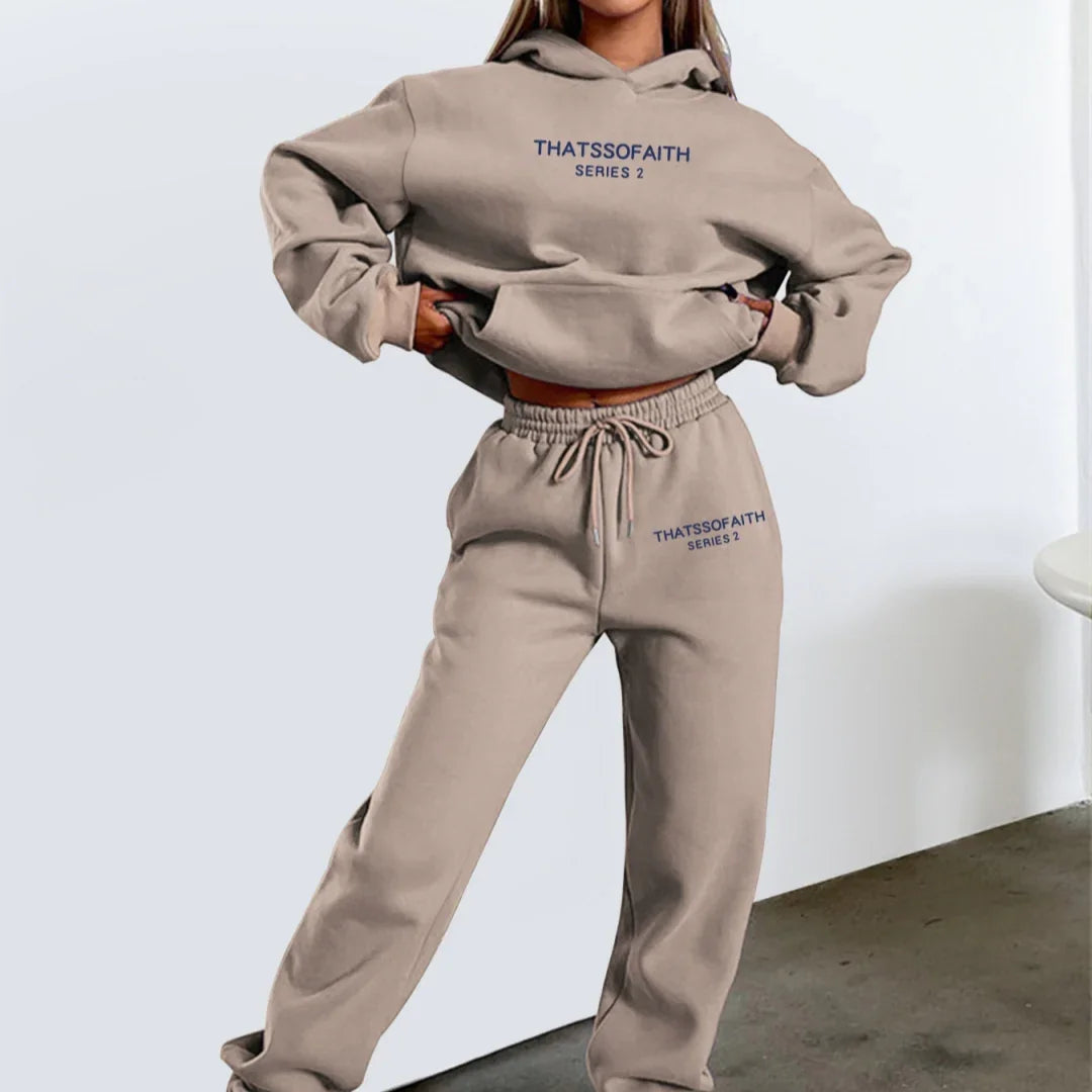 Woman wearing beige matching hoodie and sweatpants set with ThatsOfaith Series 2 logo, standing indoors