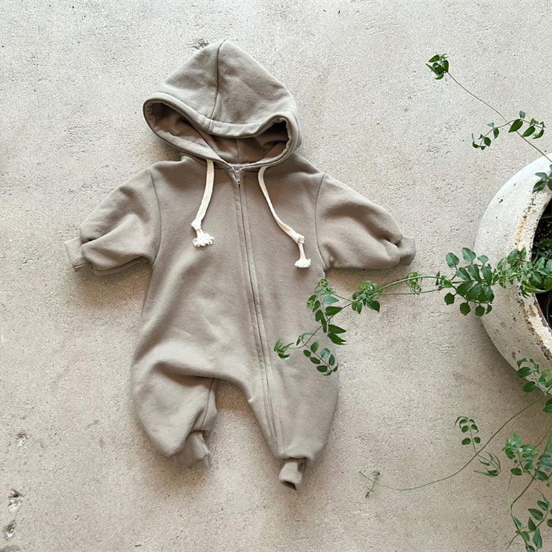 Beige baby hooded zip-up romper laid on floor near green plant in white pot