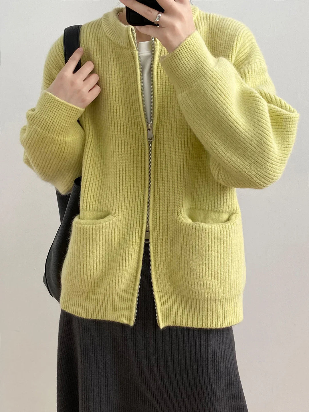 Person wearing yellow ribbed zip-up cardigan with pockets and dark ribbed skirt