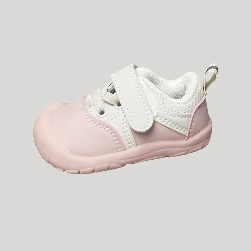 Pink and white baby sneaker with Velcro strap and padded ankle collar on gray background