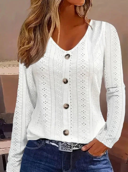 Woman wearing white long-sleeve eyelet button-up blouse paired with blue jeans and patterned belt