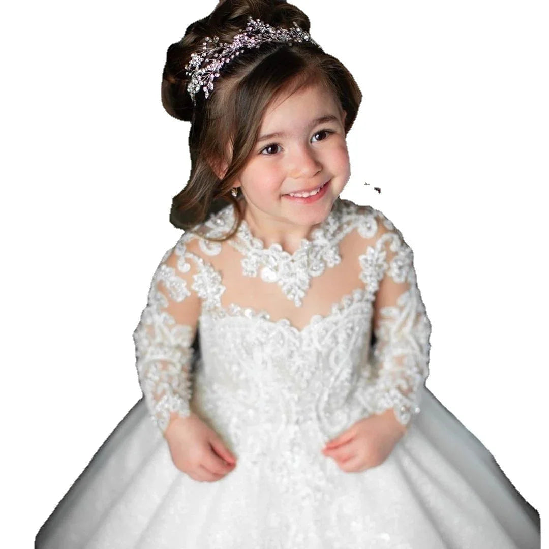 Smiling young girl in embroidered white lace dress and jeweled tiara with styled hair