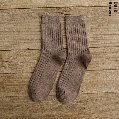 Pair of dark brown ribbed knit socks laid flat on wooden surface