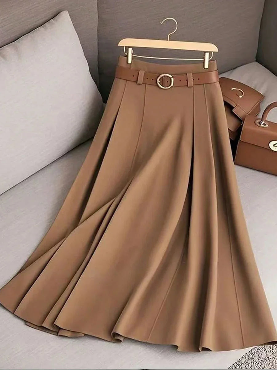 Brown pleated midi skirt with matching belt on wooden hanger, displayed on beige couch