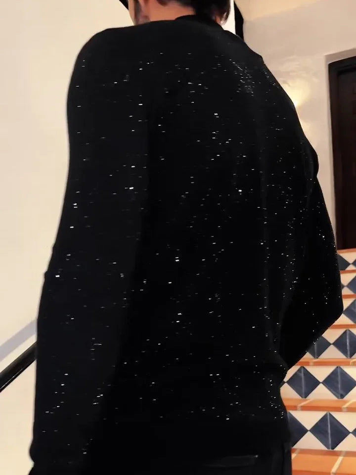 Person wearing a black glittery sweater walking up tiled stairs with black handrail indoors