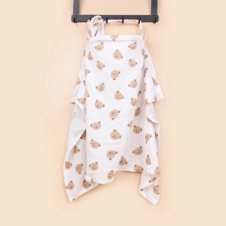 White baby muslin cloth with cute brown bear faces hanging on a black hook against beige wall