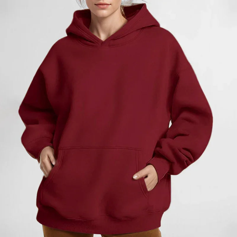 Woman wearing oversized maroon hoodie with kangaroo pocket and relaxed fit