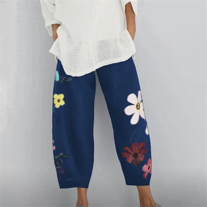 Woman wearing loose navy blue pants with colorful large floral prints, paired with a white top