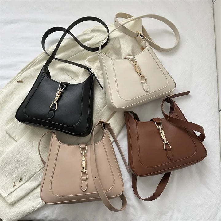 Four leather shoulder bags in black, cream, beige, and brown with gold clasps, arranged on fabric
