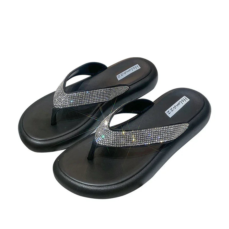 Black flip-flops with thick soles and sparkling rhinestone-embellished straps on white background