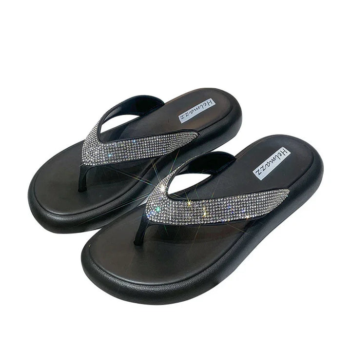 Black flip-flops with thick soles and sparkling rhinestone-embellished straps on white background
