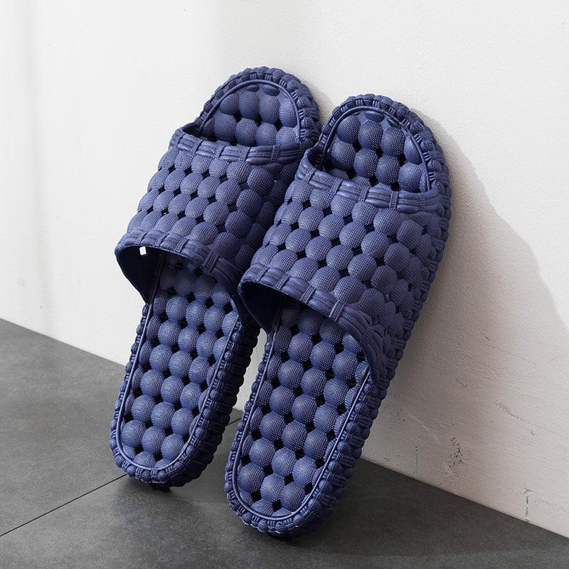 Pair of blue cushioned slippers with bubble texture on floor against white wall