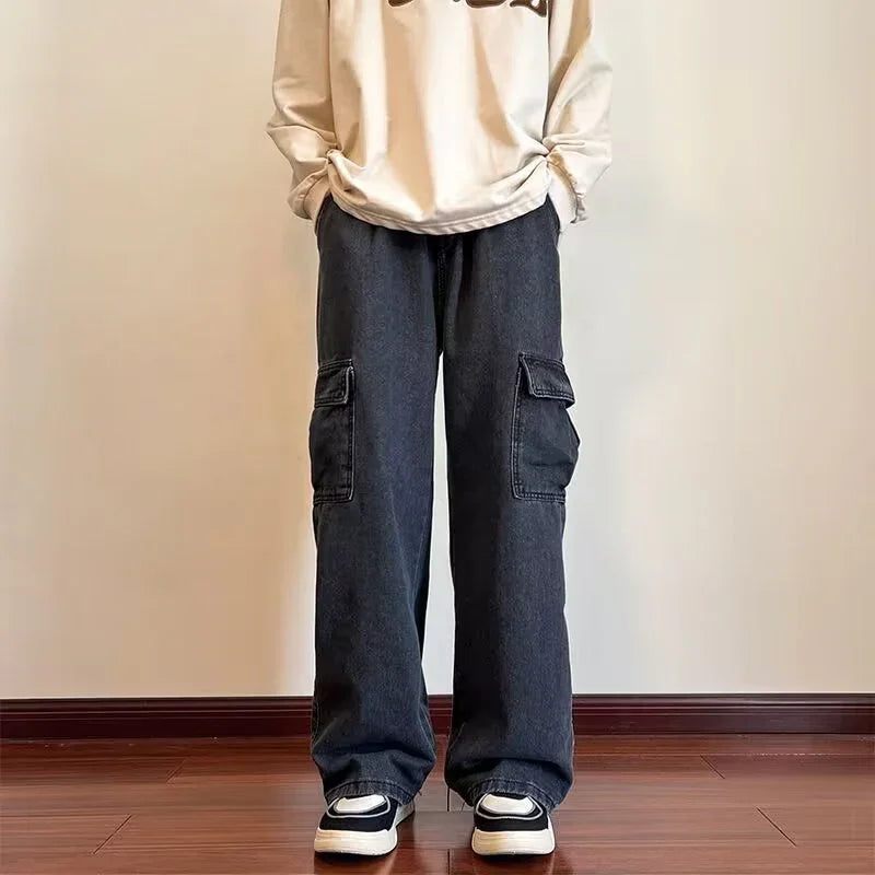 Person wearing loose black cargo pants and white graphic sweatshirt with sneakers indoors