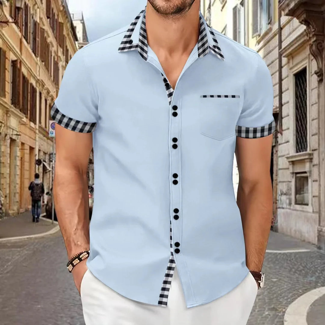 Man wearing light blue short sleeve shirt with black checkered collar and cuffs on a city street