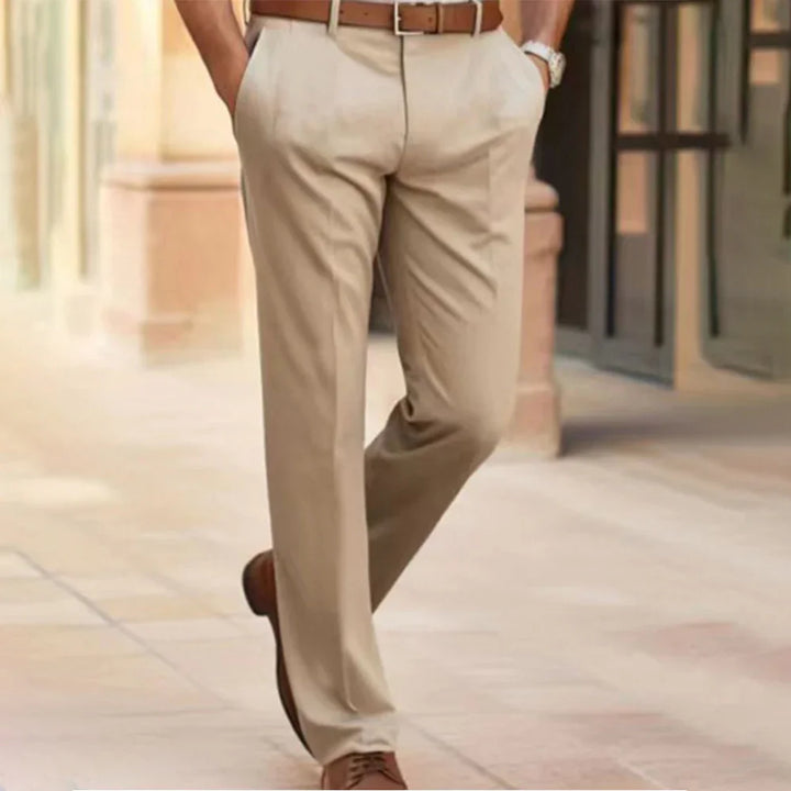 Man wearing beige cotton blend dress pants with brown belt and brown dress shoes walking outdoors
