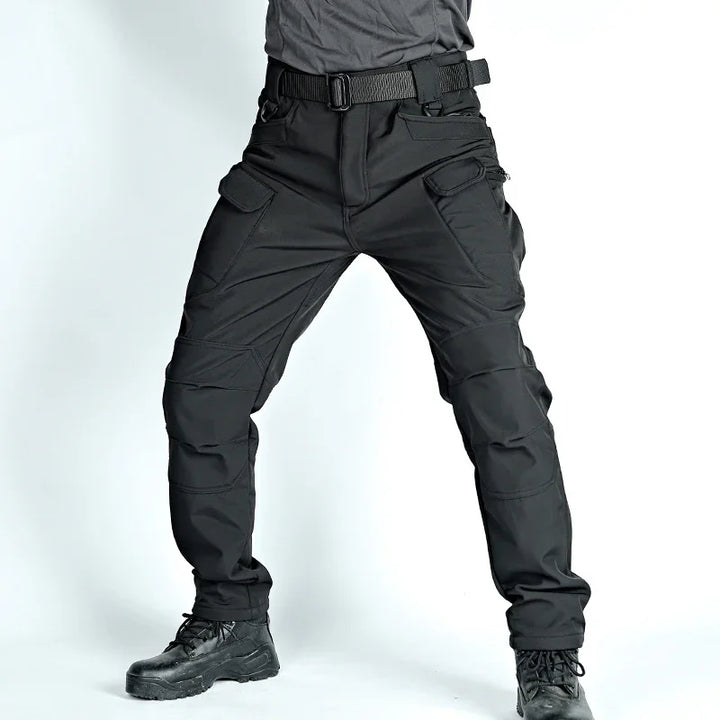 Black tactical cargo pants with multiple pockets worn with black boots and a gray shirt