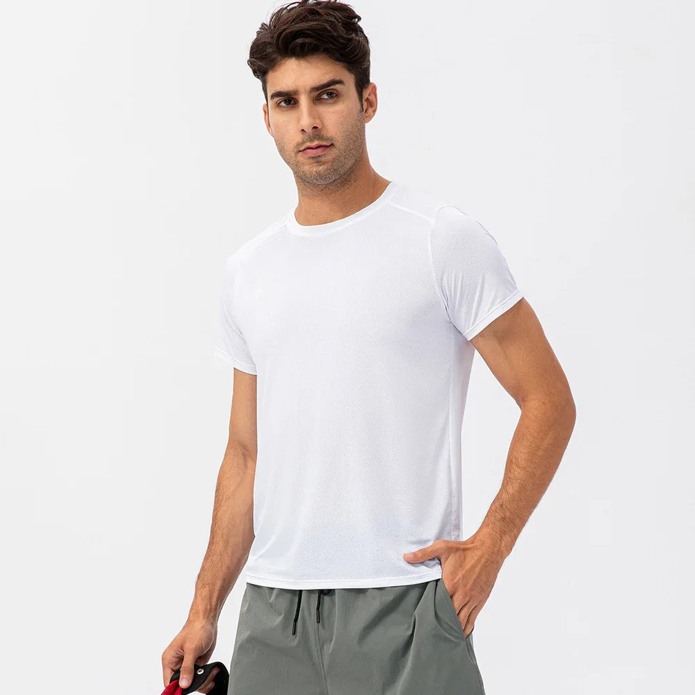 Man wearing a plain white athletic t-shirt and gray shorts against a white background