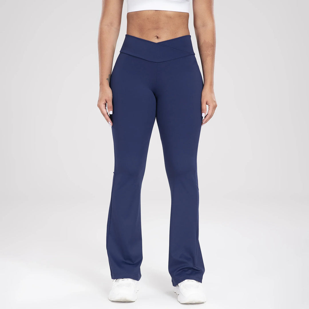 Woman wearing navy blue high-waisted flare leggings and white sneakers on light background