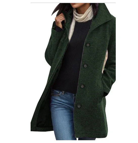Woman wearing dark green buttoned wool coat over black sweater and blue jeans with cream scarf