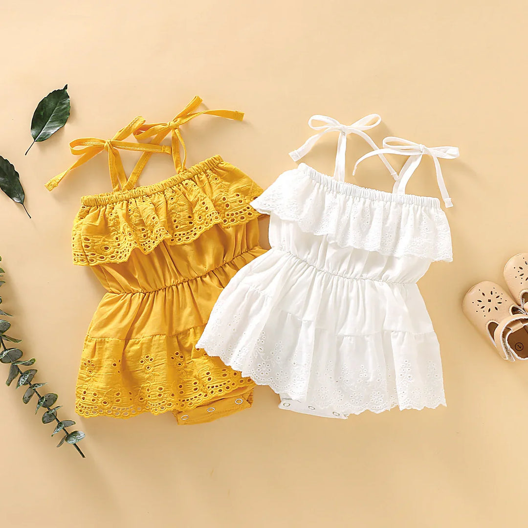 Yellow and white eyelet lace baby toddler dresses with shoulder ties and beige shoes on beige background