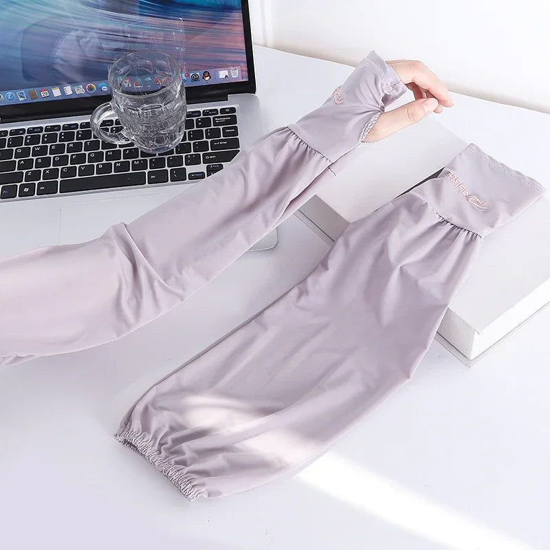 Light purple cooling arm sleeves with thumb holes on a white desk beside a laptop and glass cup