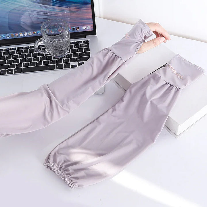 Light purple cooling arm sleeves with thumb holes on a white desk beside a laptop and glass cup