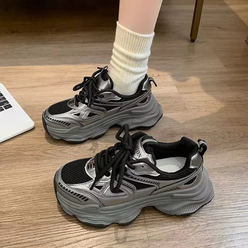 Chunky black and silver platform sneakers with thick soles on wooden floor