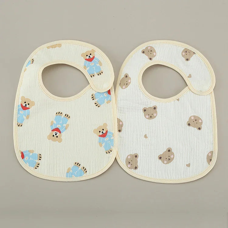 Two baby bibs with teddy bear patterns on a neutral background, soft cotton fabric
