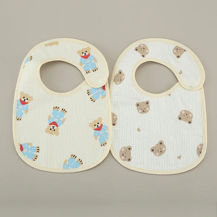 Two baby bibs with teddy bear patterns on a neutral background, soft cotton fabric