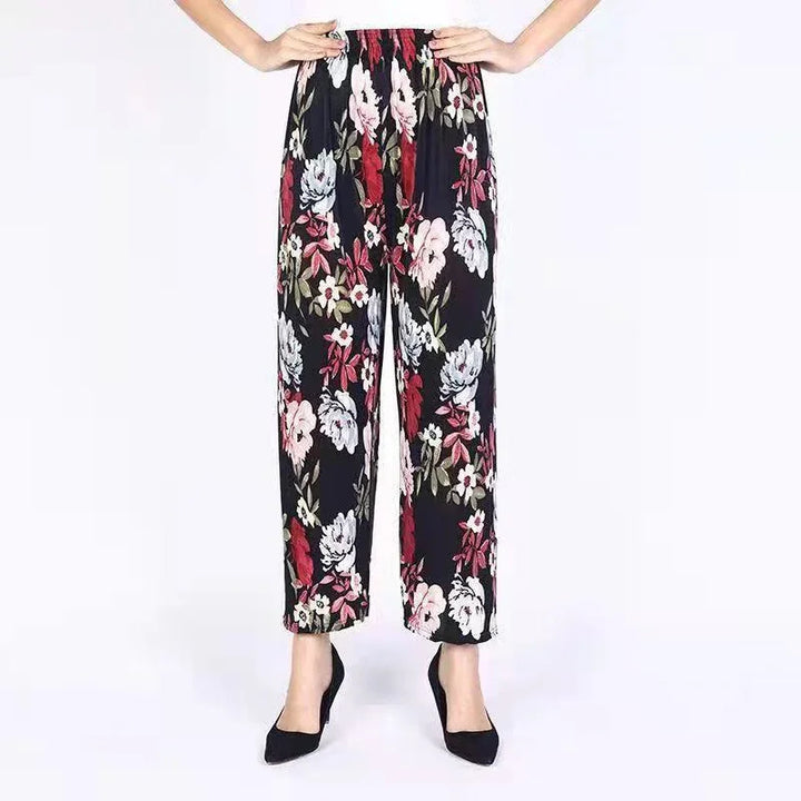 Woman wearing high-waist black floral print wide-leg pants with pink and red flowers and black heels
