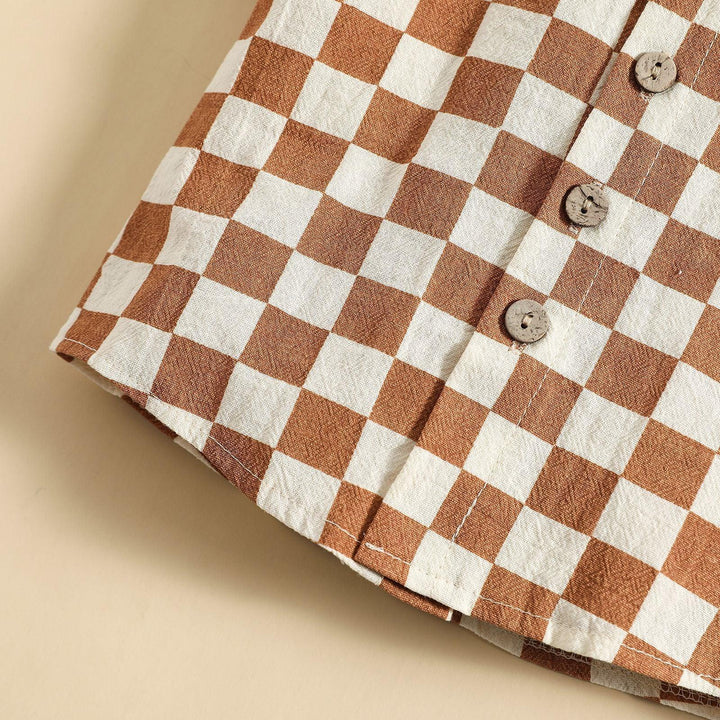 Close-up of brown and white checkered cotton fabric with wooden buttons on beige background