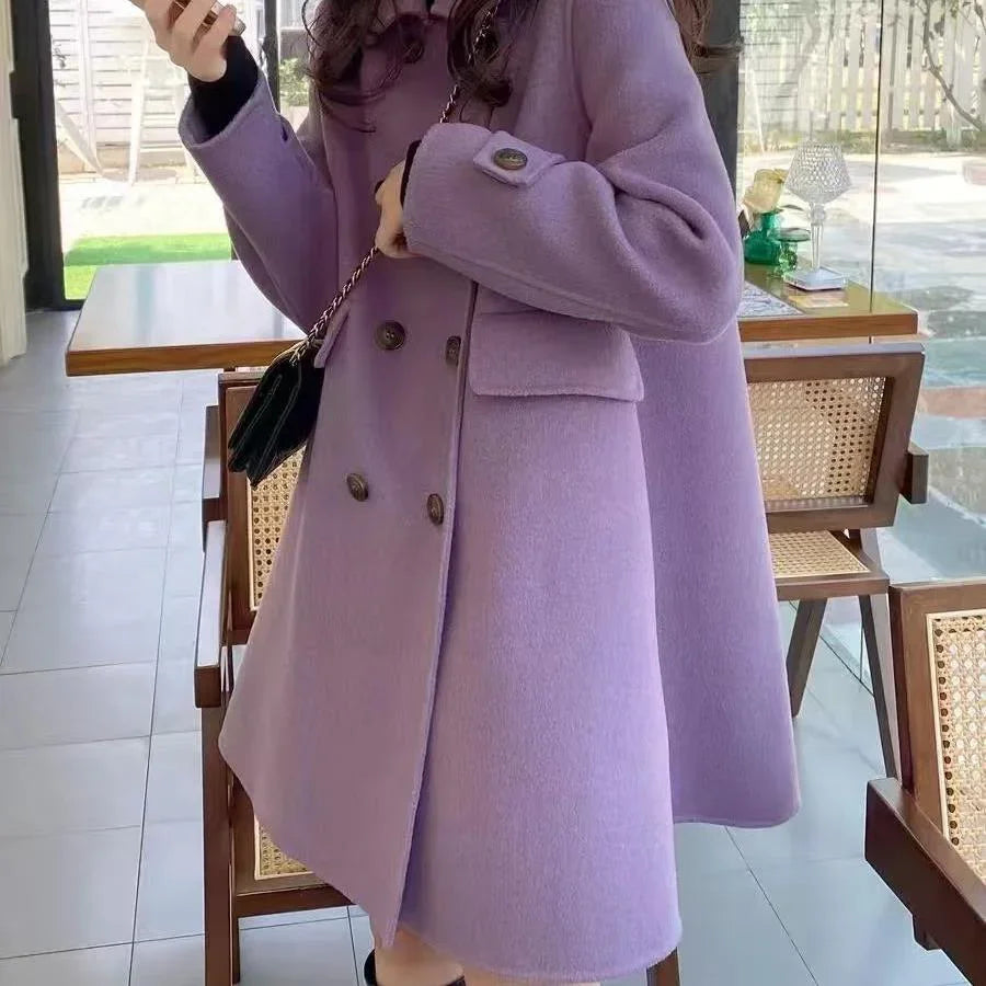 Woman wearing a double-breasted lavender wool coat with large buttons, holding a phone indoors