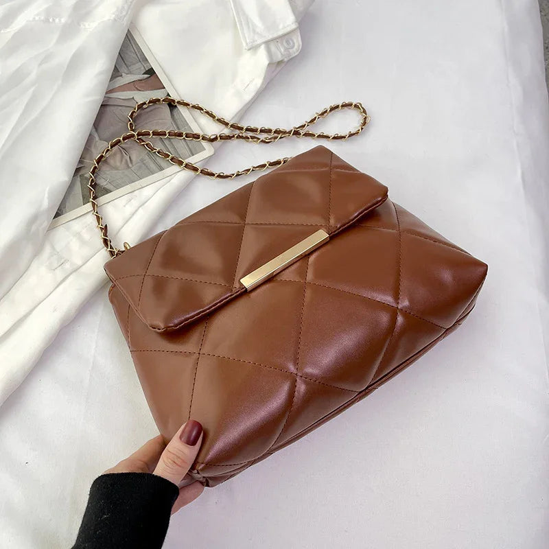 Brown quilted leather crossbody bag with gold chain strap on white fabric background