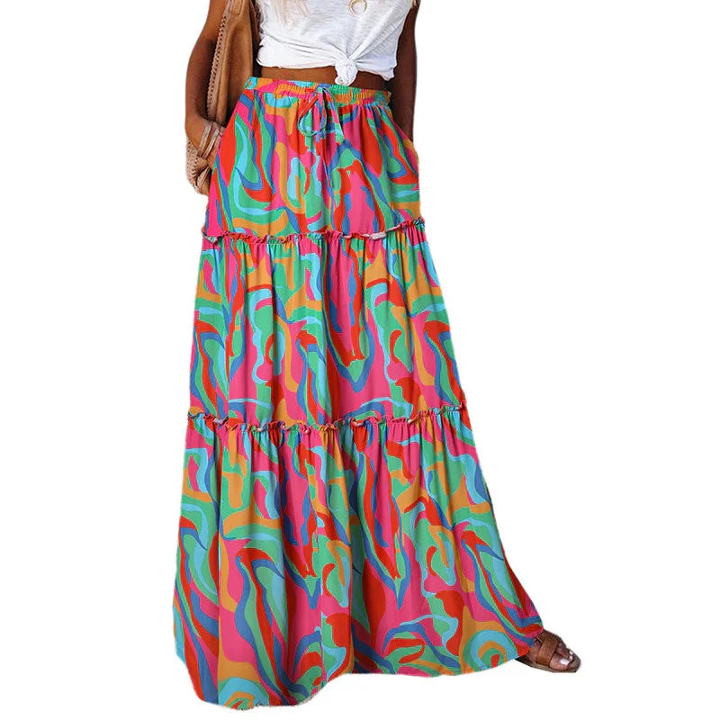 Woman wearing colorful abstract print tiered maxi skirt with white knotted top and sandals