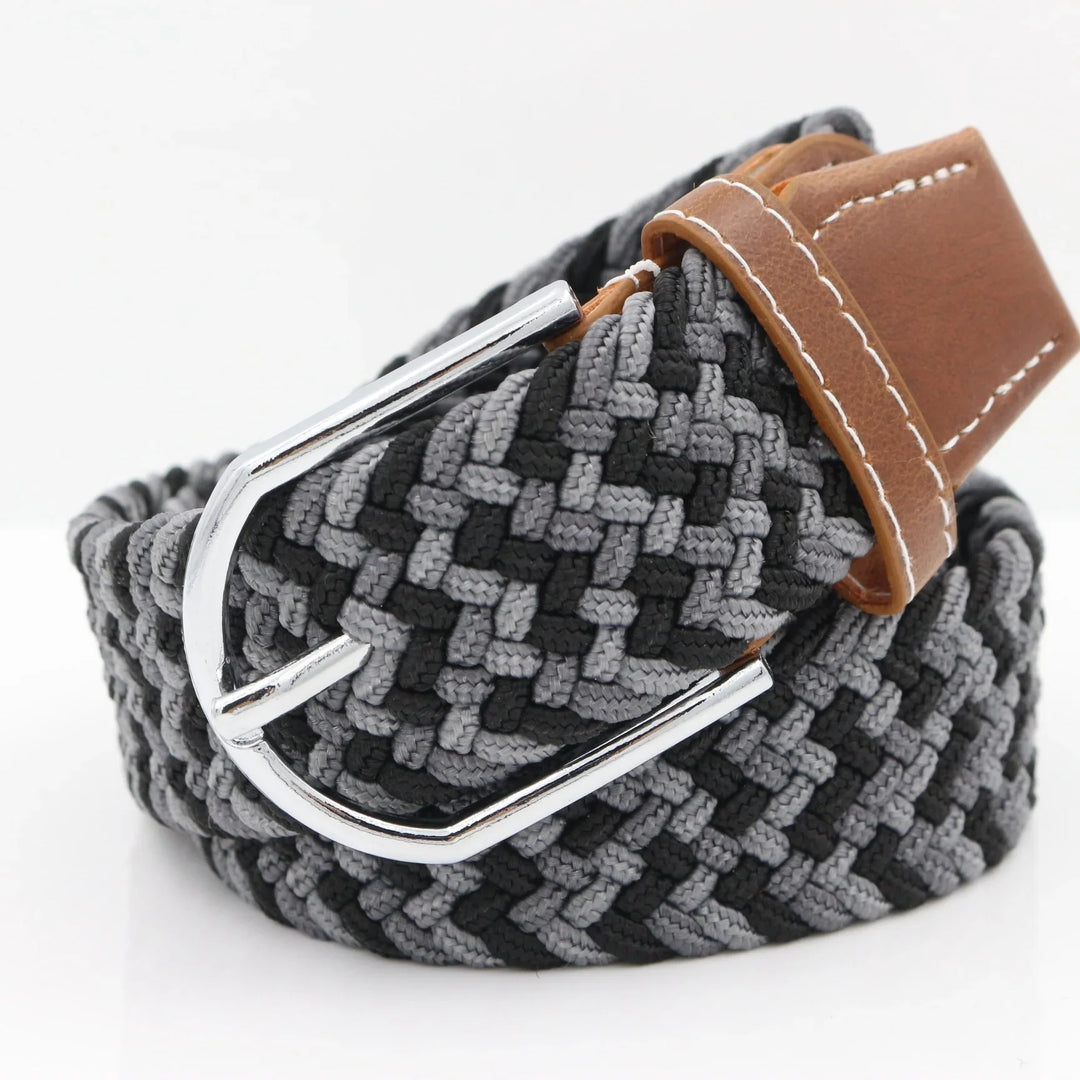 Close-up of a grey and black woven fabric belt with a silver buckle and brown leather accents