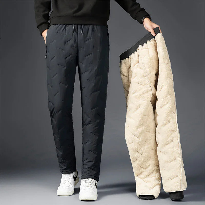 Man wearing black quilted winter pants and holding beige fleece-lined insulated pants
