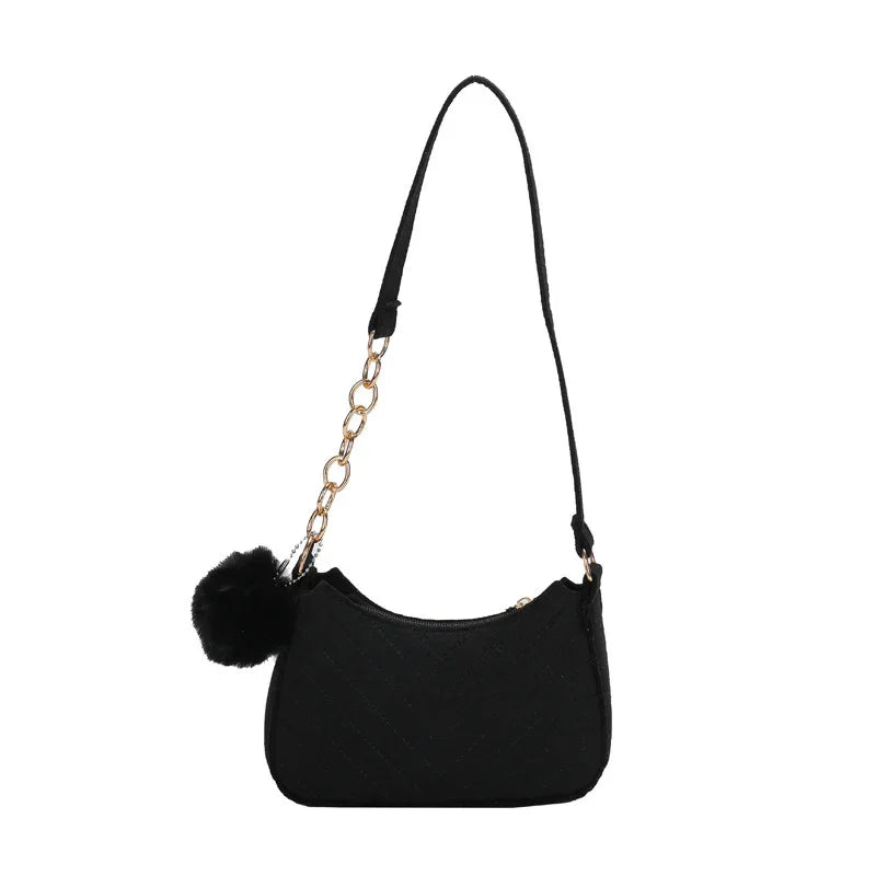 Black quilted shoulder bag with gold chain strap detail and black pom pom accessory