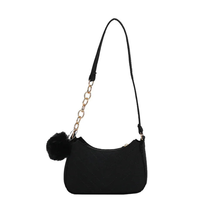 Black quilted shoulder bag with gold chain strap detail and black pom pom accessory