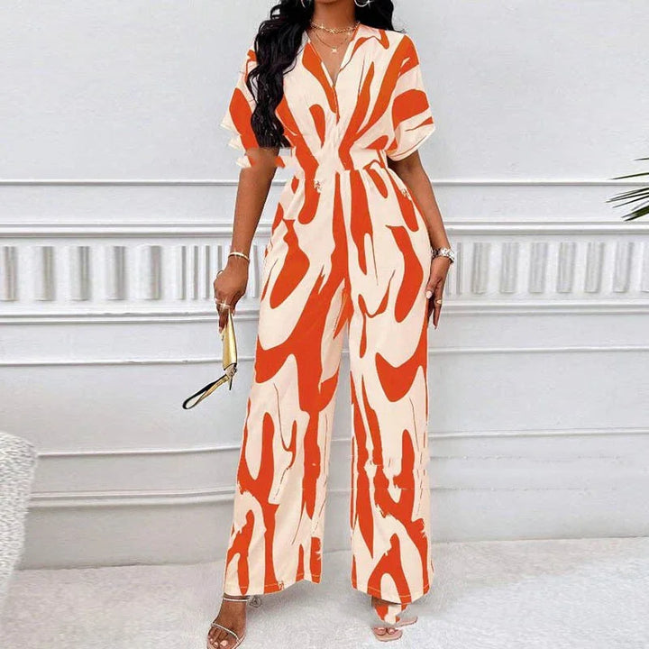 Woman wearing orange and white abstract print wide-leg jumpsuit with short sleeves and V-neck