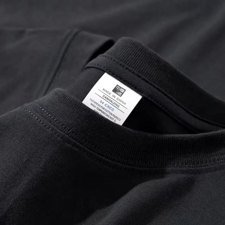 Close-up of a black cotton t-shirt neck with a white label showing washing instructions and made in China tag
