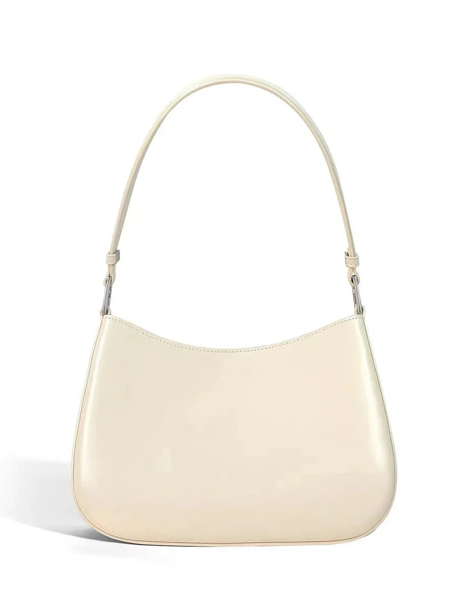 Minimalist cream leather shoulder bag with curved shape and single strap on white background