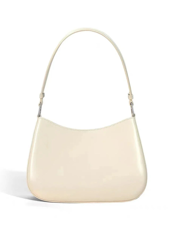 Minimalist cream leather shoulder bag with curved shape and single strap on white background