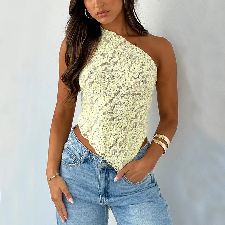 Woman wearing yellow lace one-shoulder top paired with light blue jeans and gold bracelets