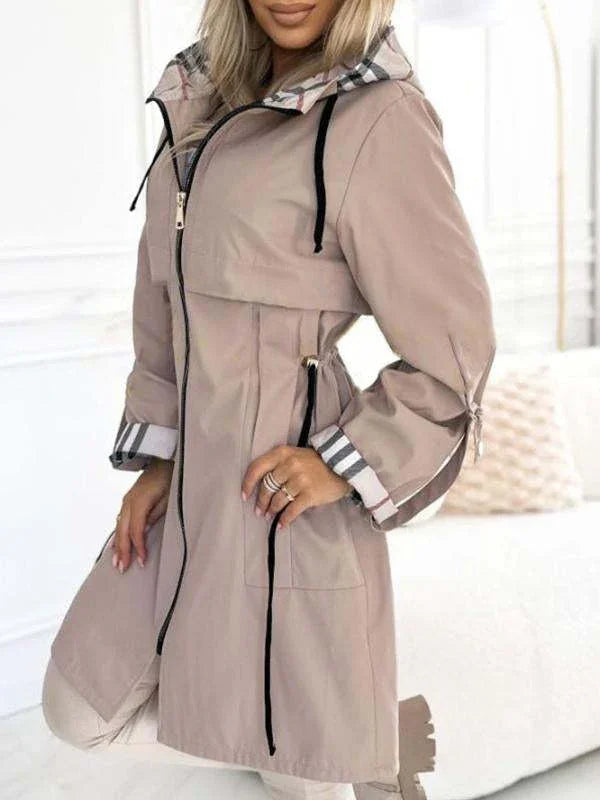 woman wearing beige mid-length hooded trench coat with plaid lining and black drawstrings