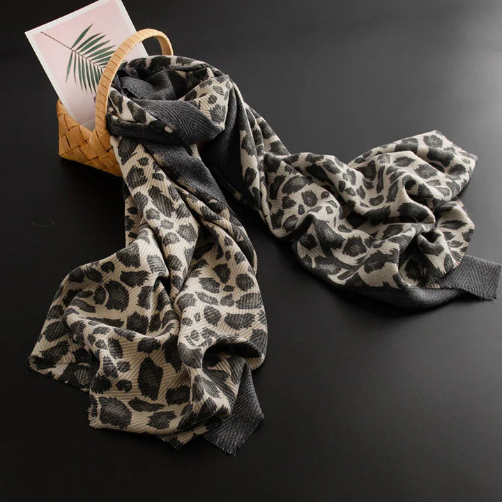 Leopard print soft scarf draped over woven basket with palm leaf card on black background
