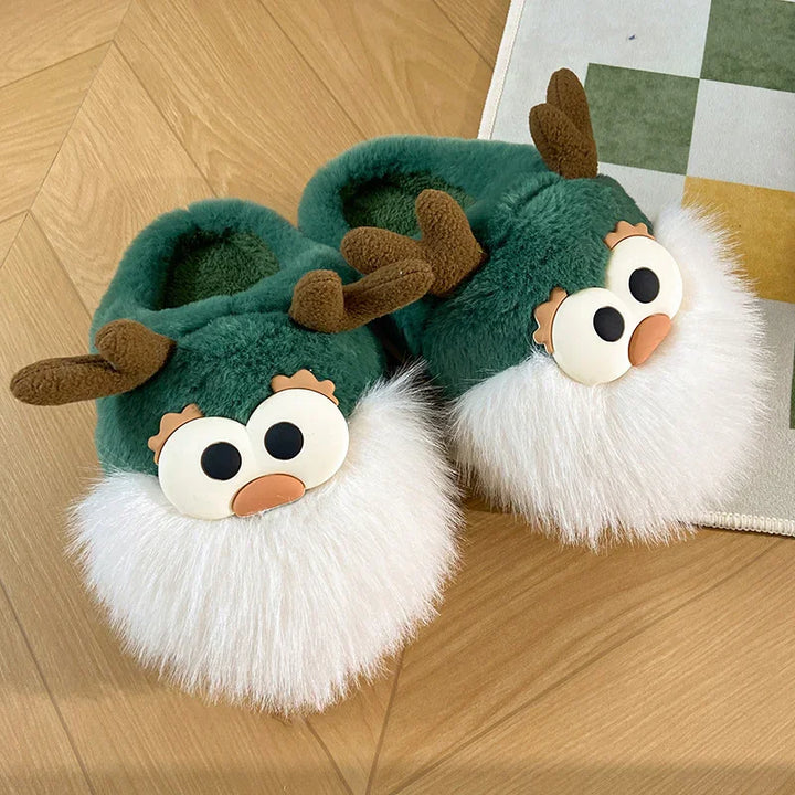 Green plush reindeer slippers with white furry beards and brown antlers on wooden floor